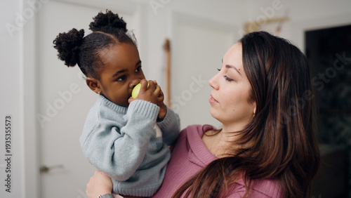Foto Mother holding toddler eating fresh green apple, representing healthy eating, fa