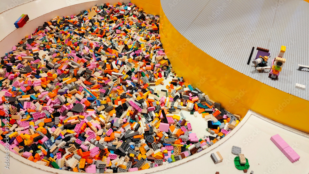 Fototapeta premium High angle view of a large circular play area filled with numerous colorful plastic Lego bricks and building blocks in a modern indoor playground on January 3, 2026 in Bangkok, Thailand.