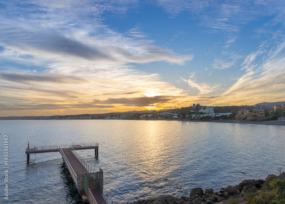 Fototapeta premium Beautiful sunset from a watchtower overlooking the sea, reflecting the sunset in the blue waters.
