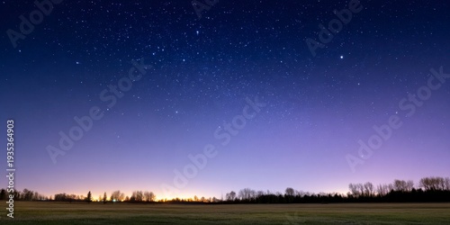 starry sky over an open field at night, with the bright stars of capricorn and sagittarius visible in the distance.