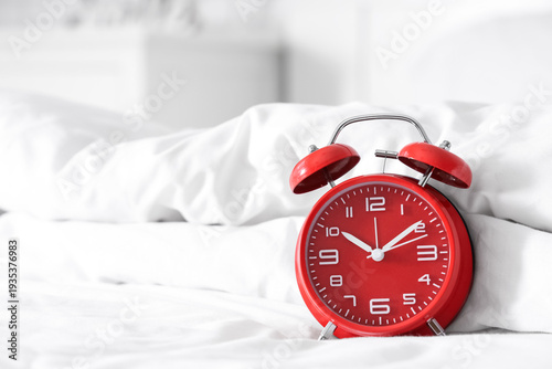 Red alarm clock on bed in l...