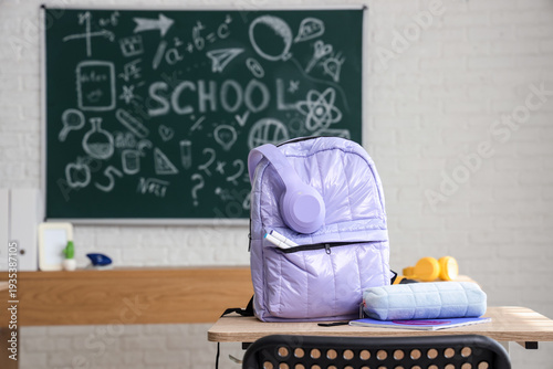 Lilac backpack with pencil case on desk in classroom