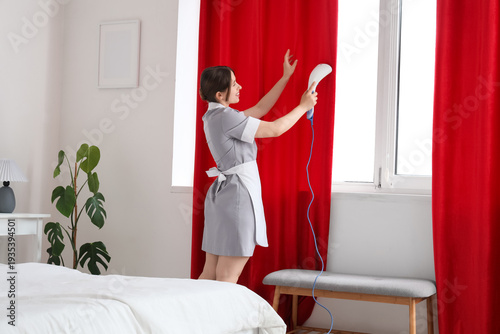 Young chambermaid steaming ...