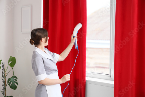 Young chambermaid steaming ...