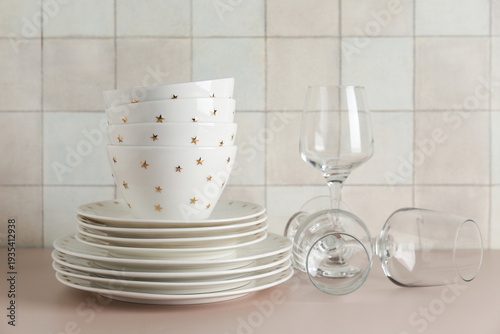 Canvastavla Clean glasses with plates, bowls and napkin on beige table against tile wall