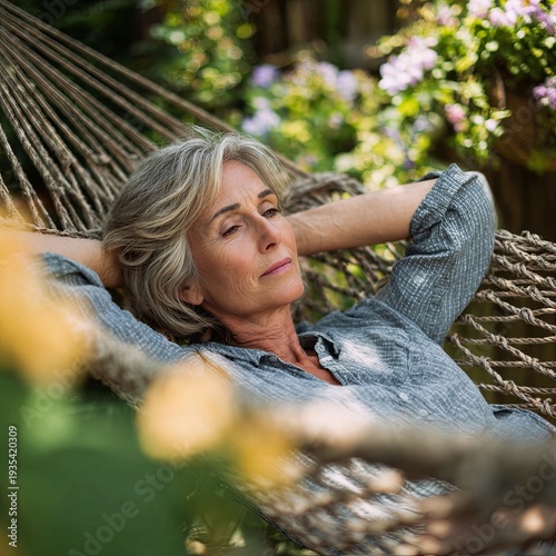 Older woman lying in a hammock and resting, quiet time in garden.