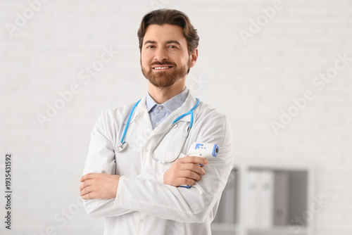 Handsome doctor with infrared thermometer in clinic