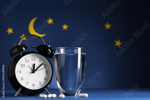 Bild auf Leinwand Melatonin pills with glass of water, alarm clock and stars on blue background