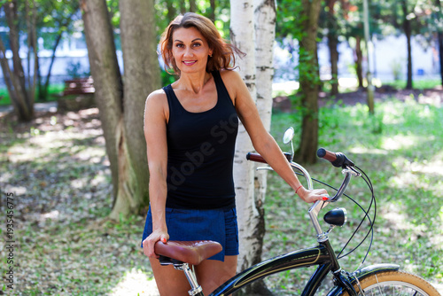 Older adult woman riding a bike in a summer park