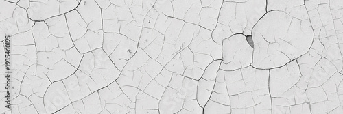 Peeling paint on the wall. Panorama of a concrete wall with old cracked flaking paint. Weathered rough painted surface with patterns of cracks and peeling. Wide panoramic grunge texture for background