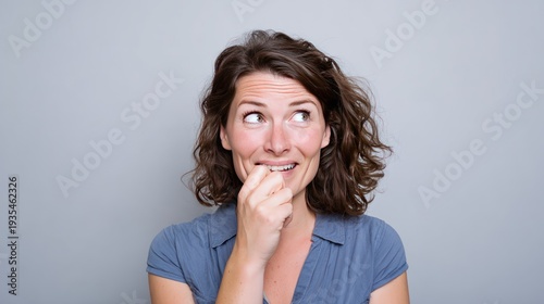 Worried woman biting her nails looking to the side.