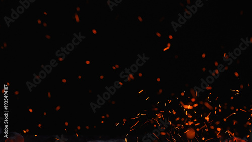 Floating orange sparks and embers rising in the dark, creating an abstract fire texture with copy space for energy, heat, welding, and night combustion concepts.