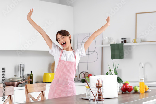 Happy young housewife at table in kitchen