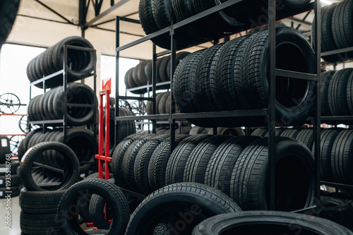 Wallpaper Mural Stacked black rubber tires on metal shelves inside a tire shop with additional tires on the floor and a red cart visible in the background Torontodigital.ca