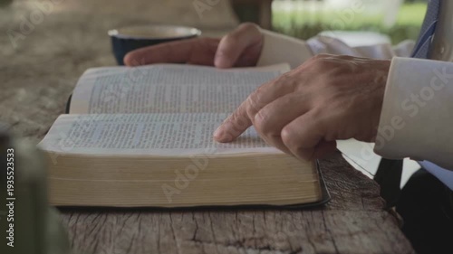white man's Hands on Open Holy Bible on wooden table Reflecting Faith at indoors