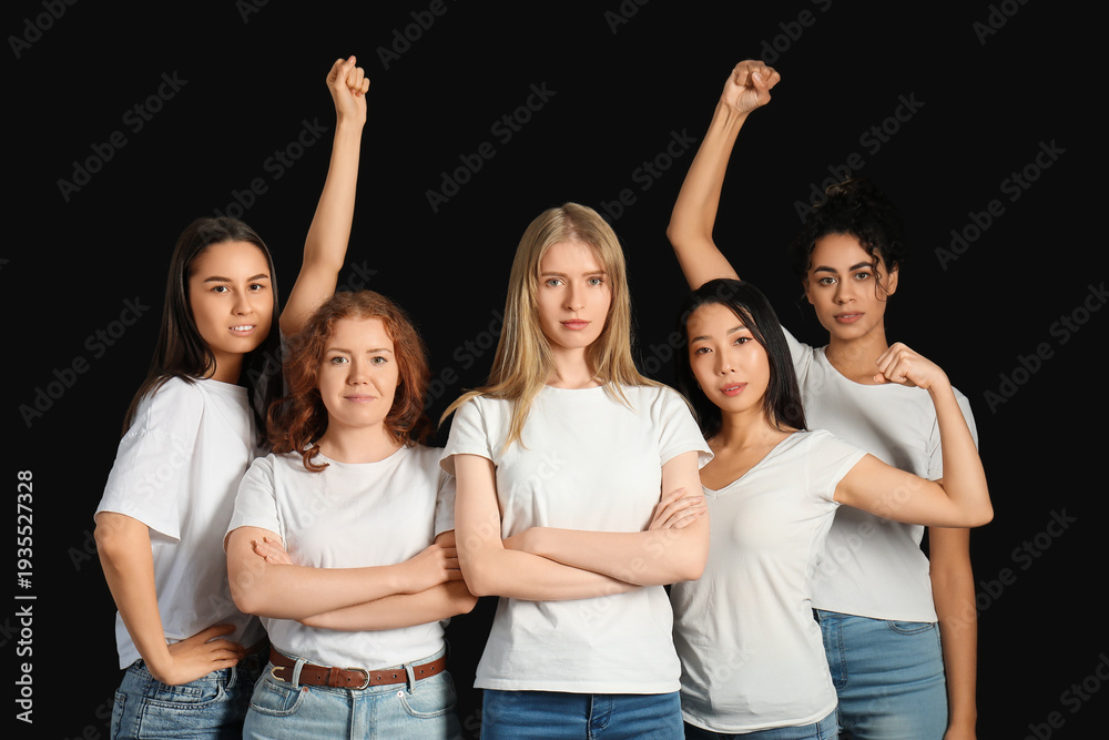 Obraz premium Beautiful young women with clenched fists showing muscles on black background. Women history month