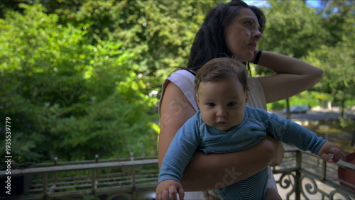 Photography Mother embracing baby on balcony, baby resting calmly in arms, mother holding se