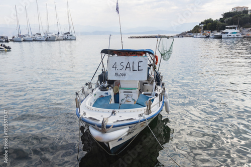 Small boat docked in marina with for sale sign.