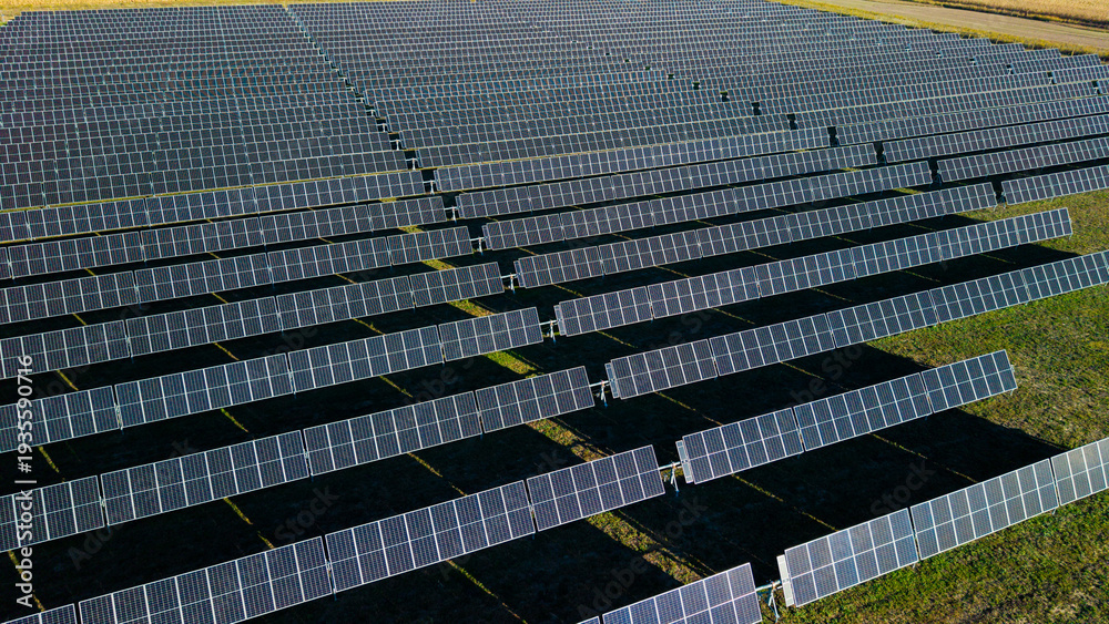 Fototapeta premium Aerial drone close view of solar power plant with long rows of photovoltaic panels generating renewable energy