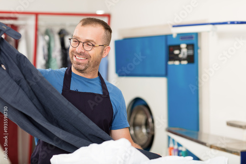 Fotografía Professional dry cleaner worker carefully inspecting a clean white sheet for quality control in a laundry shop