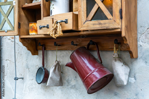 Fotografía Rustic wooden kitchen shelf with enamelware on a raw wall, vintage cupboard with old teapot and linen bags, farmhouse interior design and cottagecore style, antique garden furniture decoration