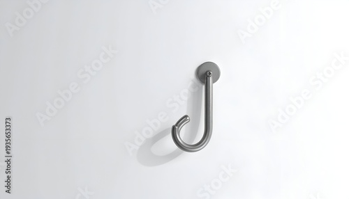 A simple, metallic J-shaped hook, mounted on a white wall, casting a soft shadow