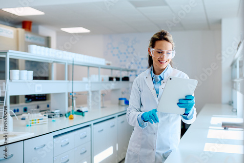 Bilde på lerret Female scientist wearing safety glasses and lab coat, smiling while analyzing da