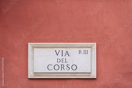 Via del Corso street sign, a classic marble plaque, mounted on an old terracotta colored building wall in Rome, Italy, a historic city and UNESCO World Heritage site