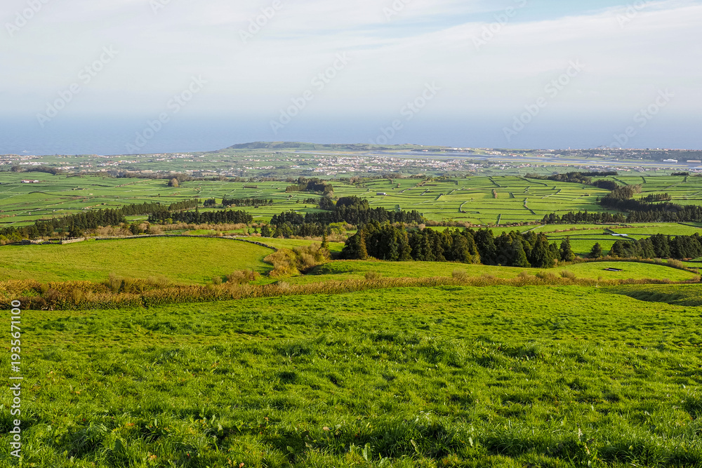 Obraz premium Coast of Terceira Island, Azores, Portugal. Cloudy day and beautiful rural landscape, green Achada Plain valley, Serra do Cume. Agricultural fields and pastures.