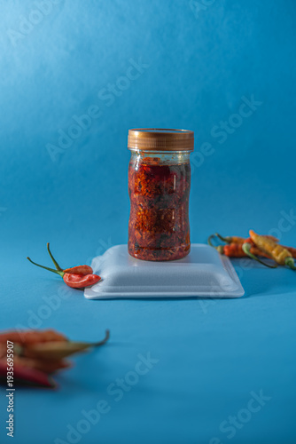 Mockup Bottle Spicy Chili Oil in Glass Jar on Blue Background