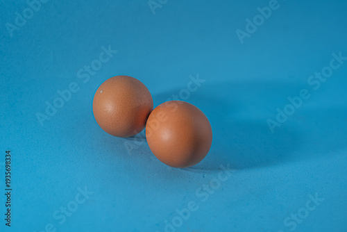 Two Brown Eggs on Blue Background