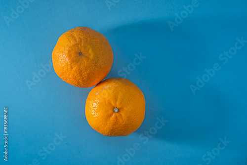 Two fresh oranges on a blue background