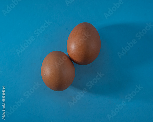 Two Brown Eggs on Blue Background