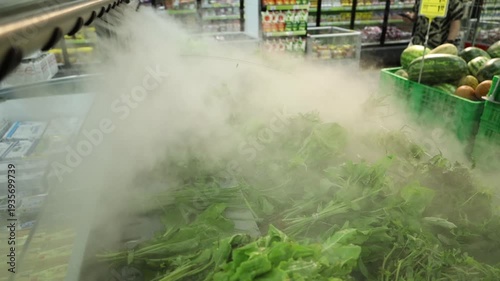 Fresh greens and vegetables displayed in a supermarket with a fine mist cooling system. highlights freshness, quality, and modern food retail.