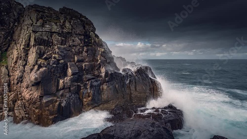 Ocean Waves Powerfully Crashing Against a Dramatic Dark Rock Cliff on a Stormy Day