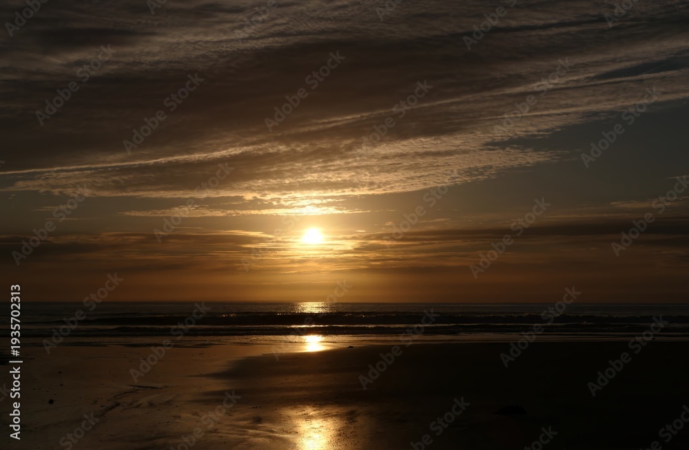 Fototapeta premium Golden Ocean Sunset with Dramatic Sky and Beach Reflections