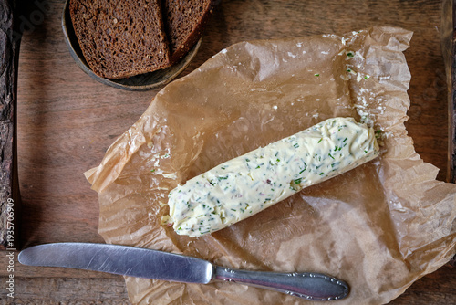 Fotografie Homemade herb butter log with fresh chives on parchment paper.