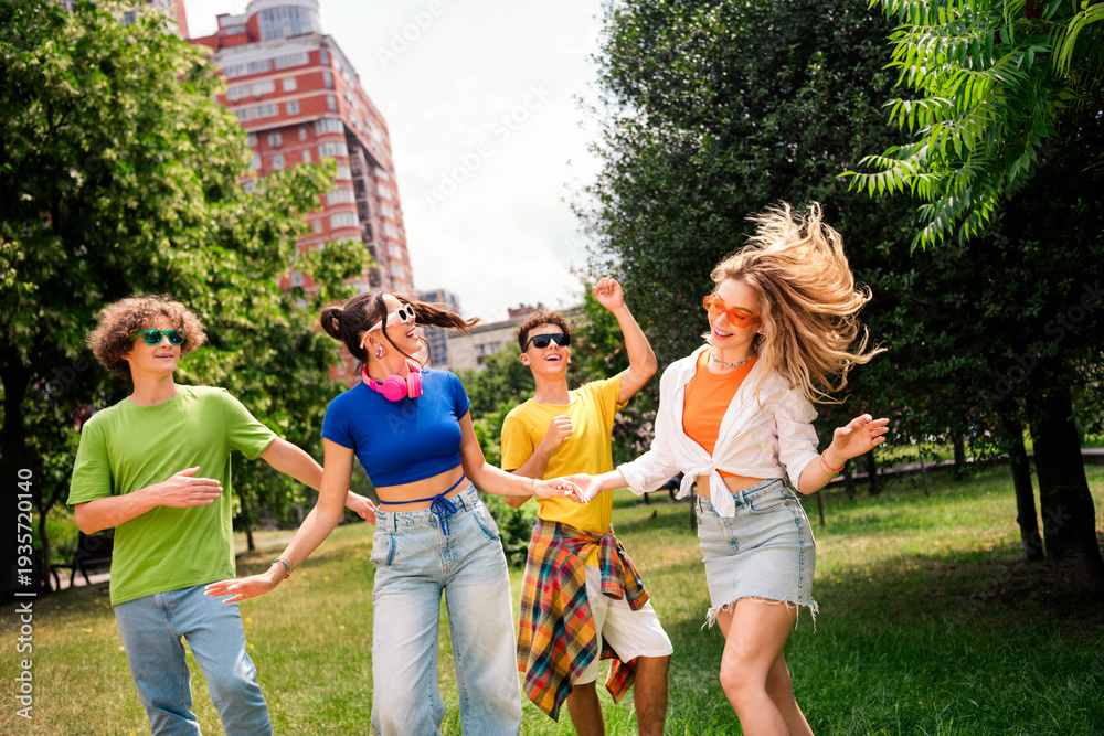 Fototapeta premium Young friends enjoying outdoor time in a city park under daylight, wearing casual attire and laughing while having fun