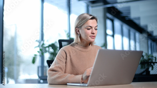 A woman is sitting at a desk with a laptop in front of her