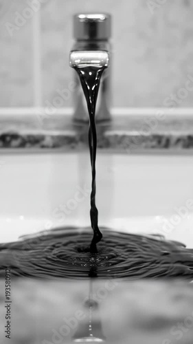 Dark viscous liquid pours from faucet into a sink