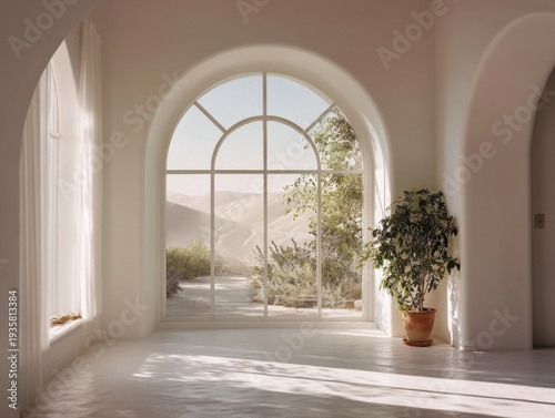 Soft sunlight streams through large arched window. Minimalist room features white walls and floor. Potted plant sits beside window, adding greenery. Distant hills visible beyond glass panes