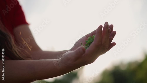 Woman cupping mint leaves, sunlit field background with warm backlight as she inhales scent, intimate moment of mindfulness and calm, gentle smile and relaxed posture suggesting ritual of aromatherapy