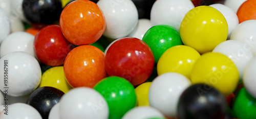A close-up image of vibrant, colorful gumballs; their bright candy coating is shown in a colorful mixture
