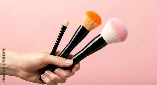 Hand Holding Set of Professional Makeup Brushes on Pink Background - Beauty Artist Tools & Cosmetic Equipment Concept