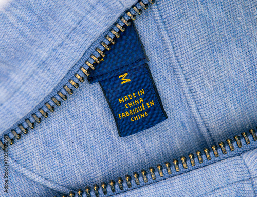 Photography A close-up of a blue jacket showing a sewn-in label stating it was made in China, with a metallic zipper