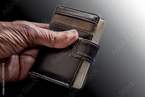 Close-up of a hand holding a slim brown leather wallet with visible credit cards, showcasing modern cashless transactions and personal finance
