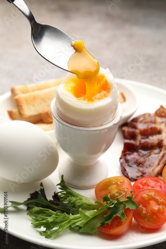 Tasty breakfast. Eating soft boiled egg at table, closeup