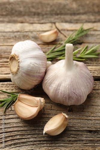 Fresh garlic and rosemary on wooden table, closeup