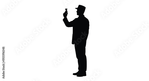 A man in a hat and jacket uses a smartphone holding it up to take a photo or record a video silhouette