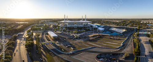 Miami Gardens, Florida - 23 February 2026: Aerial view of Hard Rock Stadium bathed in the golden light of the setting sun, surrounded by the winding race track and lush greenery.